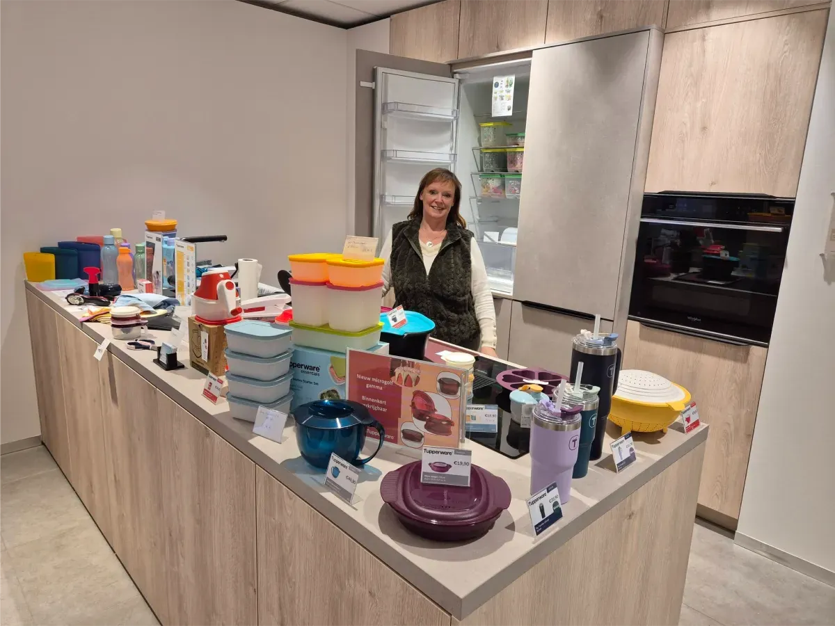 Nina naast een keukeneiland vol Tupperware tijdens een demonstratie